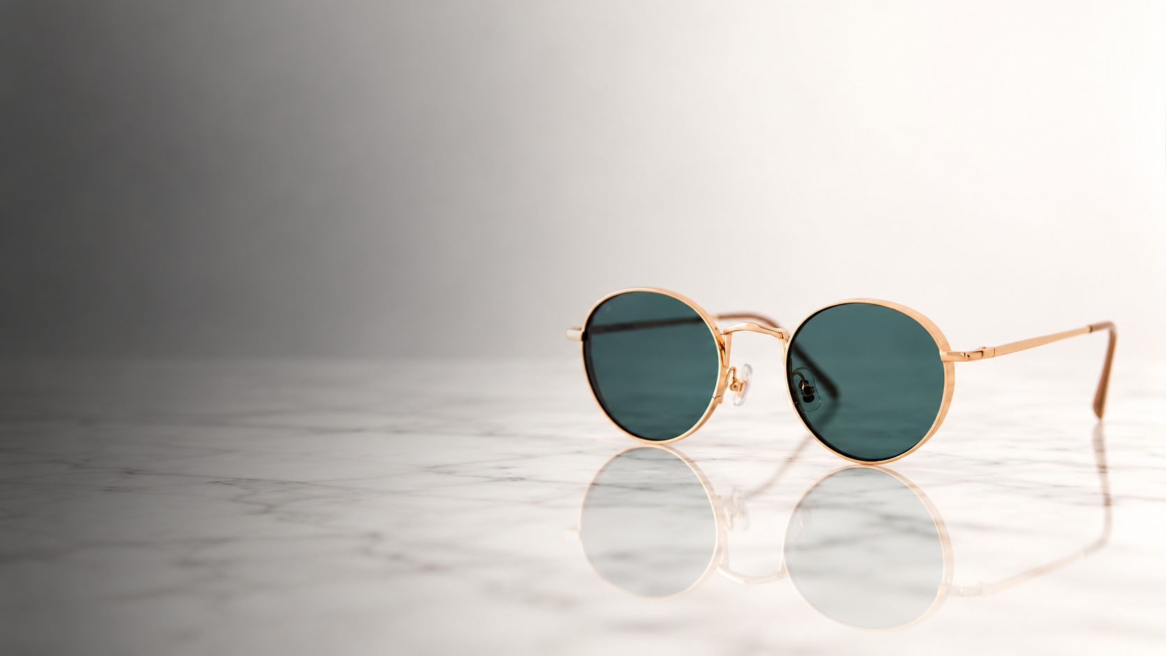 Round gold sunglasses resting on a reflective surface